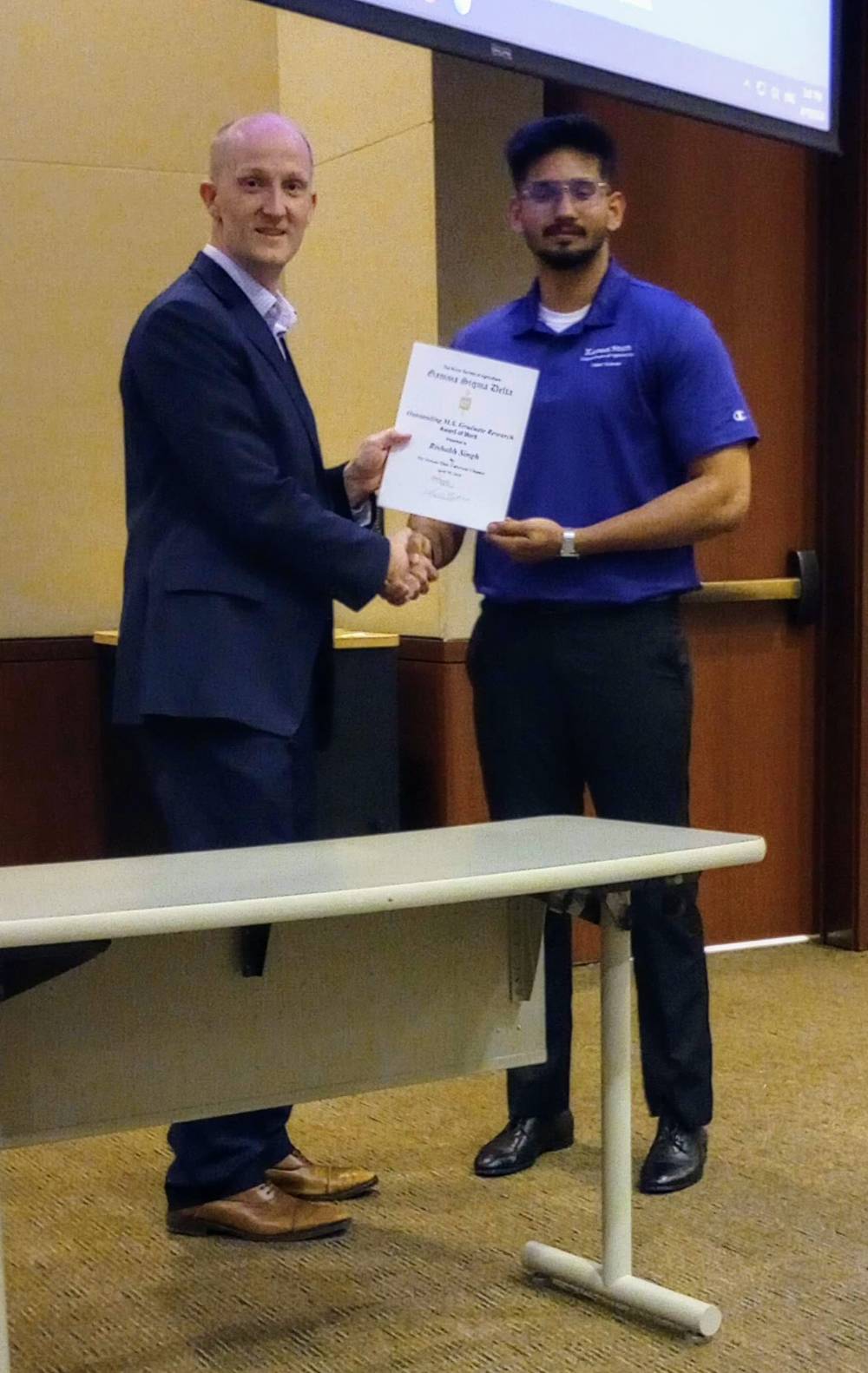 Logan Britton presenting Outstanding MS Graduate Student Research award to Rishabh Singh