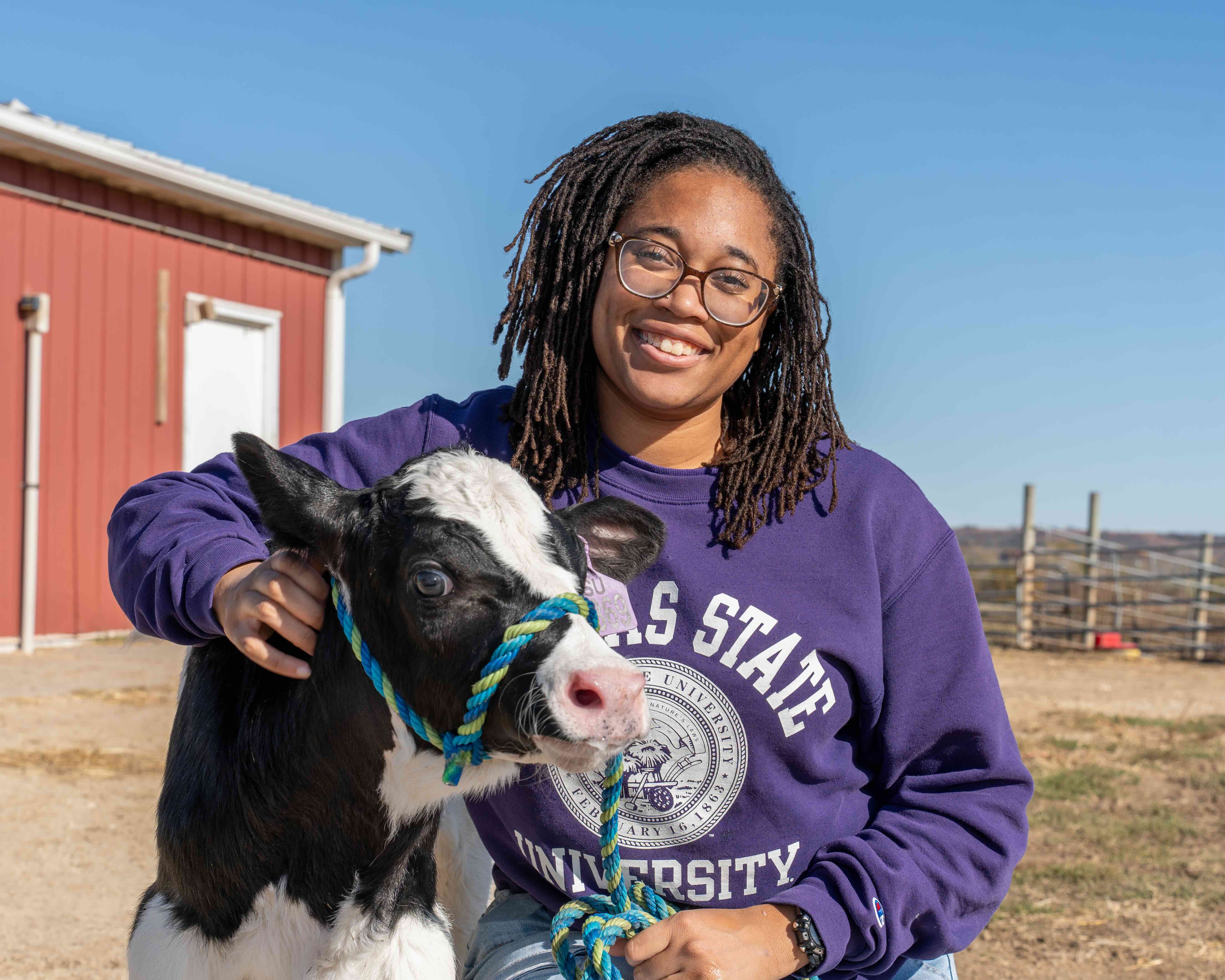 Lailah Bias crouched down with baby dairy calf